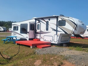 A white RV with a door, windows, and a small table. - What a View Cheticamp (Chéticamp)