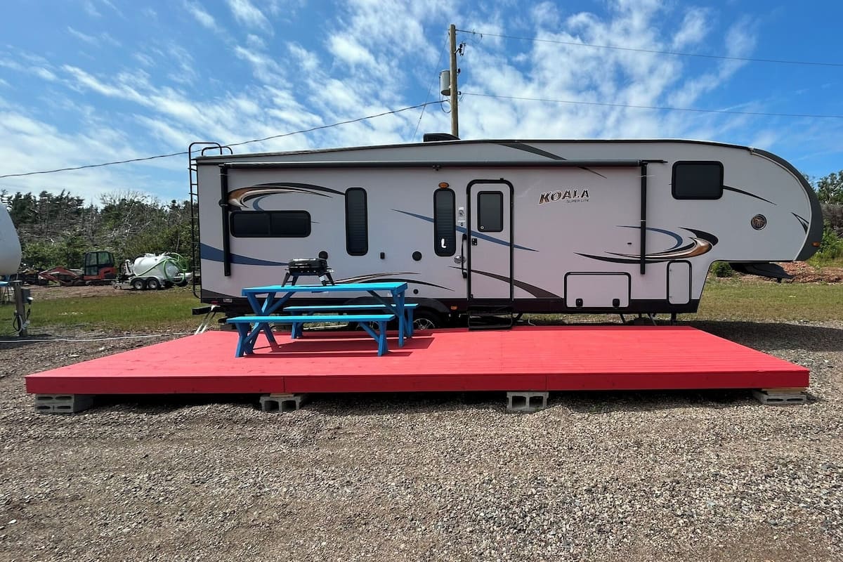 Una caravana KOALA Super Life con una mesa de picnic y una plataforma roja.