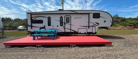 Una caravana KOALA Super Life con una mesa de picnic y una plataforma roja.