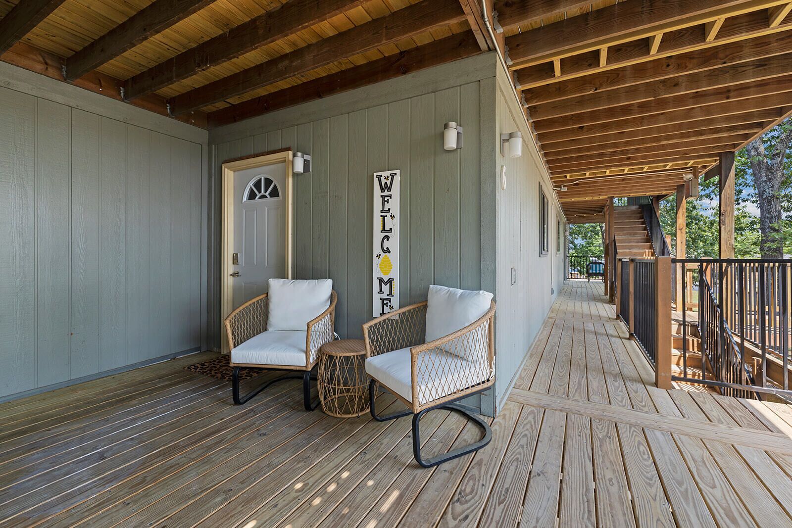 Une véranda avec deux fauteuils en osier et une terrasse en bois.