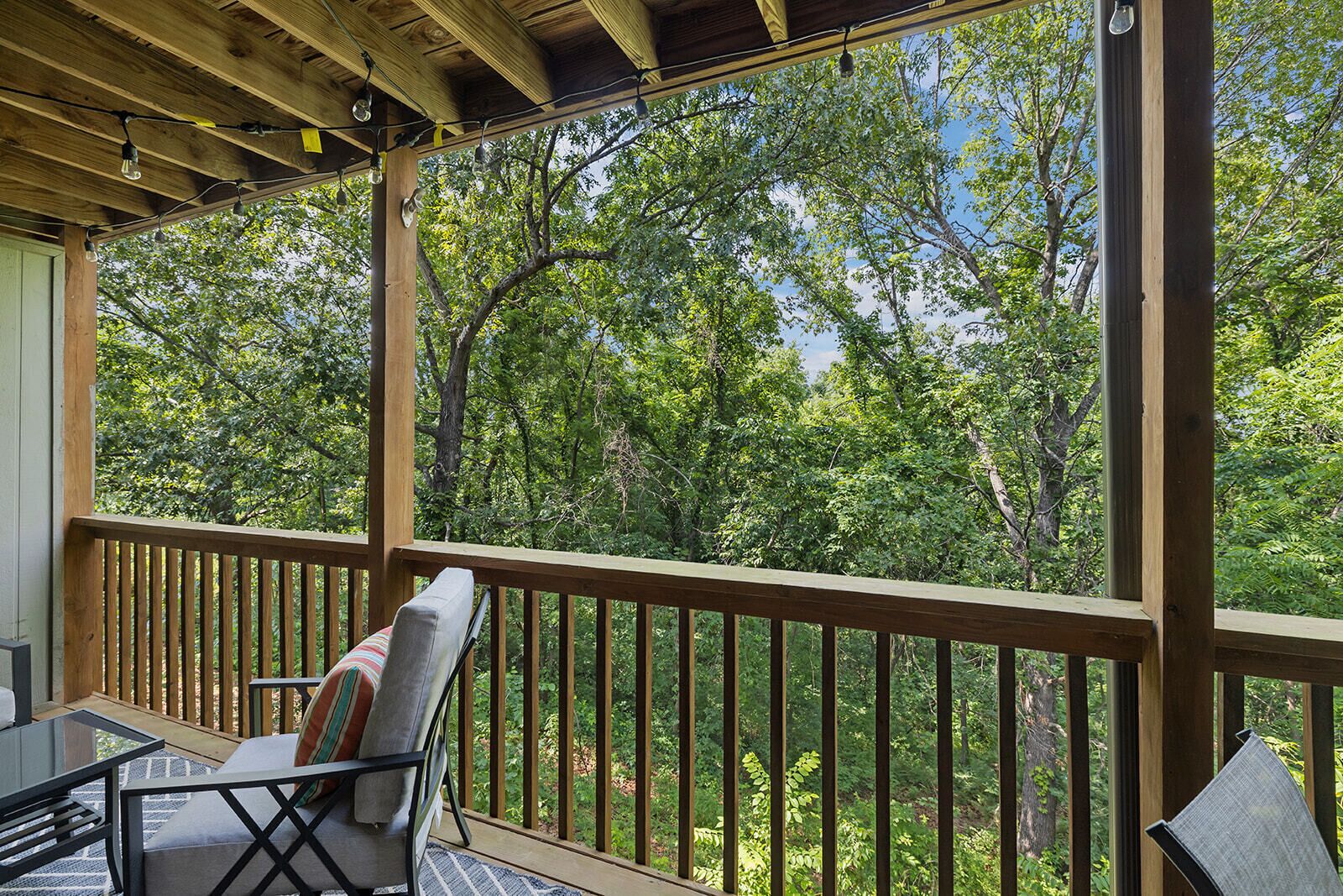 Un espace extérieur abrité, doté d’une terrasse en bois, d’une chaise avec un coussin et d’une table.