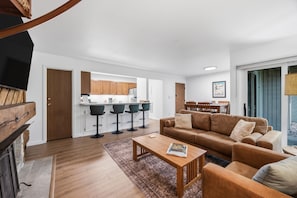 A modern living room with a sofa, coffee table, and a kitchen in the background. - Modern 3BR Keystone Condo · Sleeps 6 · Walk to Lake, Minutes to Golf (Keystone)