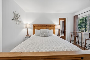 A neatly arranged bedroom with a bed, two bedside lamps, a small table with chairs, and a window with curtains. - Modern 3BR Keystone Condo · Sleeps 6 · Walk to Lake, Minutes to Golf (Keystone)