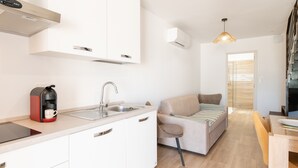 A modern kitchen with a coffee maker, sink, and white cabinets. There is a sofa and a dining table in the living area. - Apartment 'La Dolce Vita 6' with Sea View, Wi-Fi and Air Conditioning (Borgo)