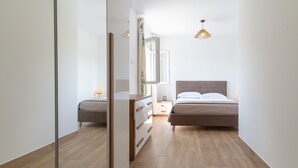 A bedroom with a bed, bedside table, lamp, dresser, and a mirror. - Apartment 'La Dolce Vita 6' with Sea View, Wi-Fi and Air Conditioning (Borgo)