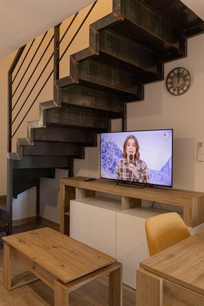 Moderni sisustus, jossa on portaikko, televisio ja puuhuonekalut.