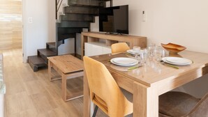 Un comedor con mesa de madera, sillas y una escalera.