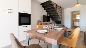 A modern kitchen with white cabinets, a built-in oven, and a dining area with a wooden table and chairs. - Apartment 'Residence La Dolce Vita' with Sea View, Wi-Fi and Air Conditioning (Borgo)