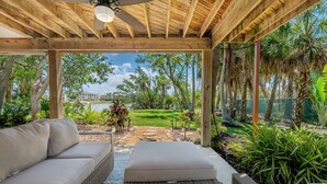 Un'area salotto all'aperto riparata, con vista su un giardino curato e un edificio sullo sfondo.
