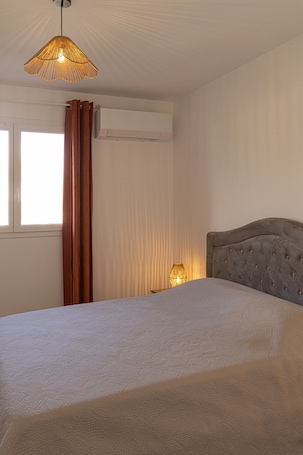 Une chambre à coucher avec un lit, un luminaire suspendu, une table de chevet et une fenêtre avec des rideaux.. Appartement « La Dolce Vita 9 » avec vue mer, Wi-Fi et climatisation