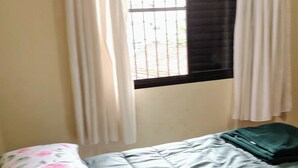 A room with a bed, a window with curtains, and a wall.