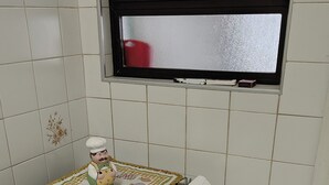 A kitchen with a gas stove, oven, and a window above the sink.