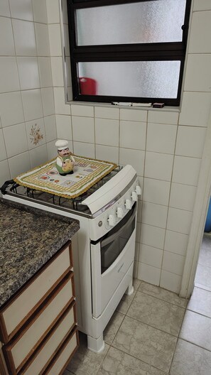 Una cocina con estufa a gas, horno y ventana sobre el lavadero.