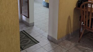 A hallway with a tiled floor, a wooden chair, a small table, and a mirror on the wall.