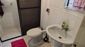 Un baño con inodoro, lavabo y zona de ducha.