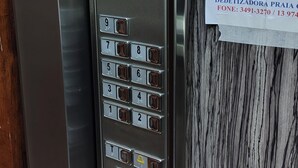 An elevator control panel with a digital display, keypad, and a sign with information about elevator capacity and usage restrictions.