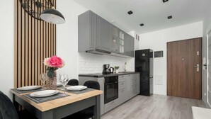 Een moderne keuken met grijze kastjes, een zwarte koelkast en een houten eettafel, gedekt met borden en glazen.