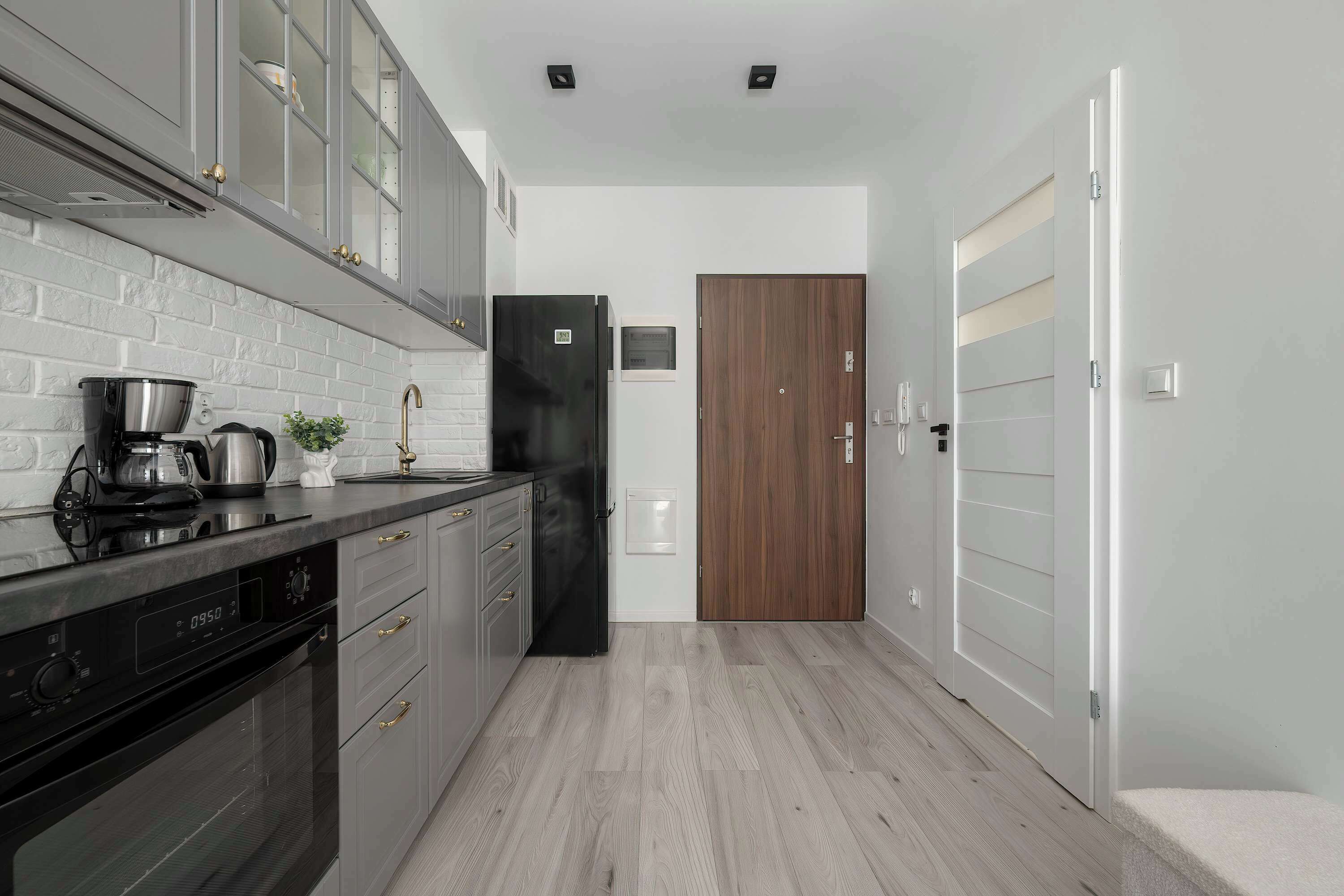 Una cocina con horno empotrado, cafetera y refrigerador.