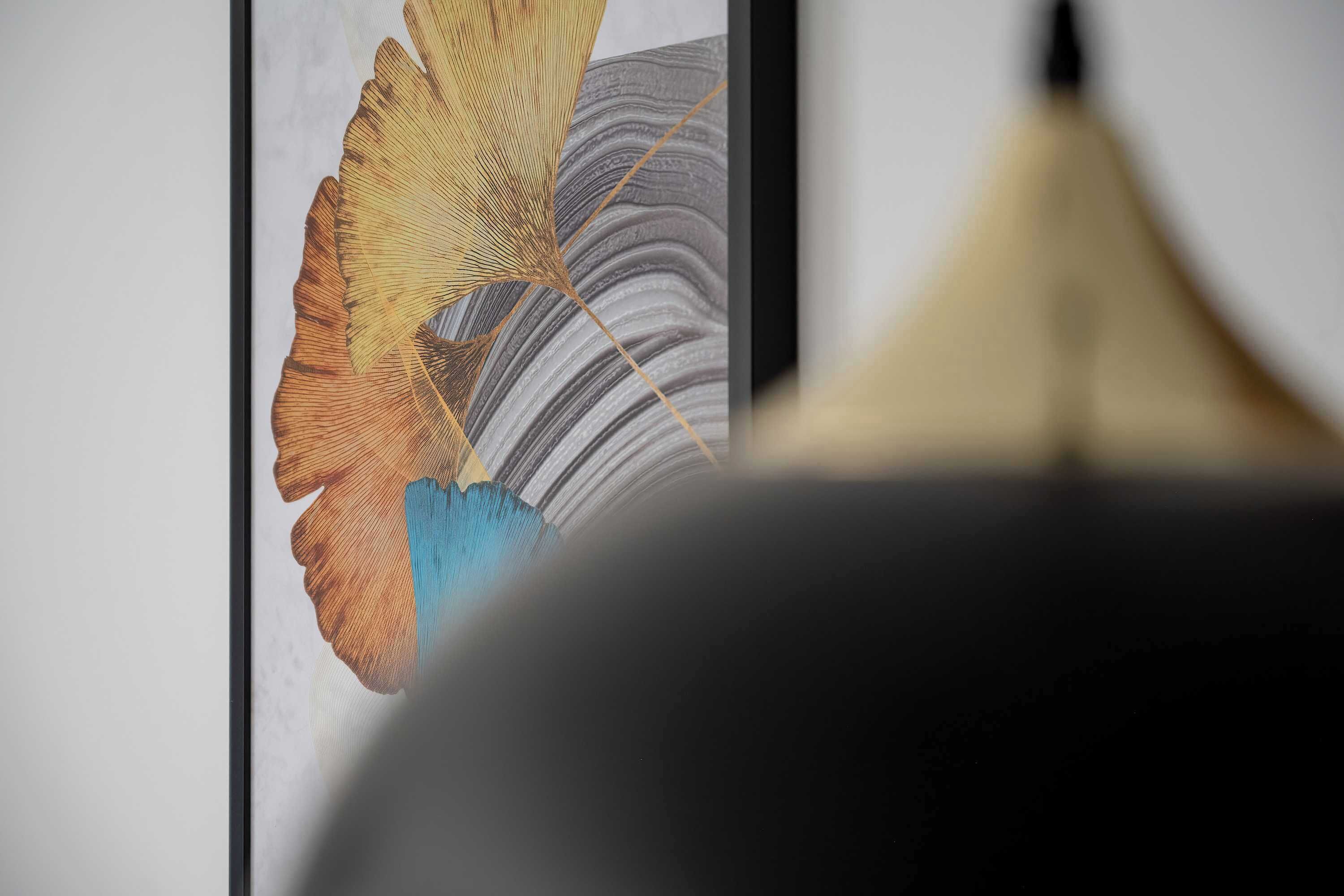 A framed artwork with abstract patterns and a dark, rounded object in the foreground.
