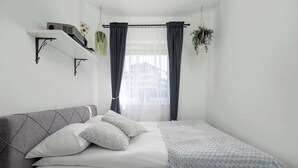 Een slaapkamer met een bed, een plank met een projecter, en een raam met gordijnen.