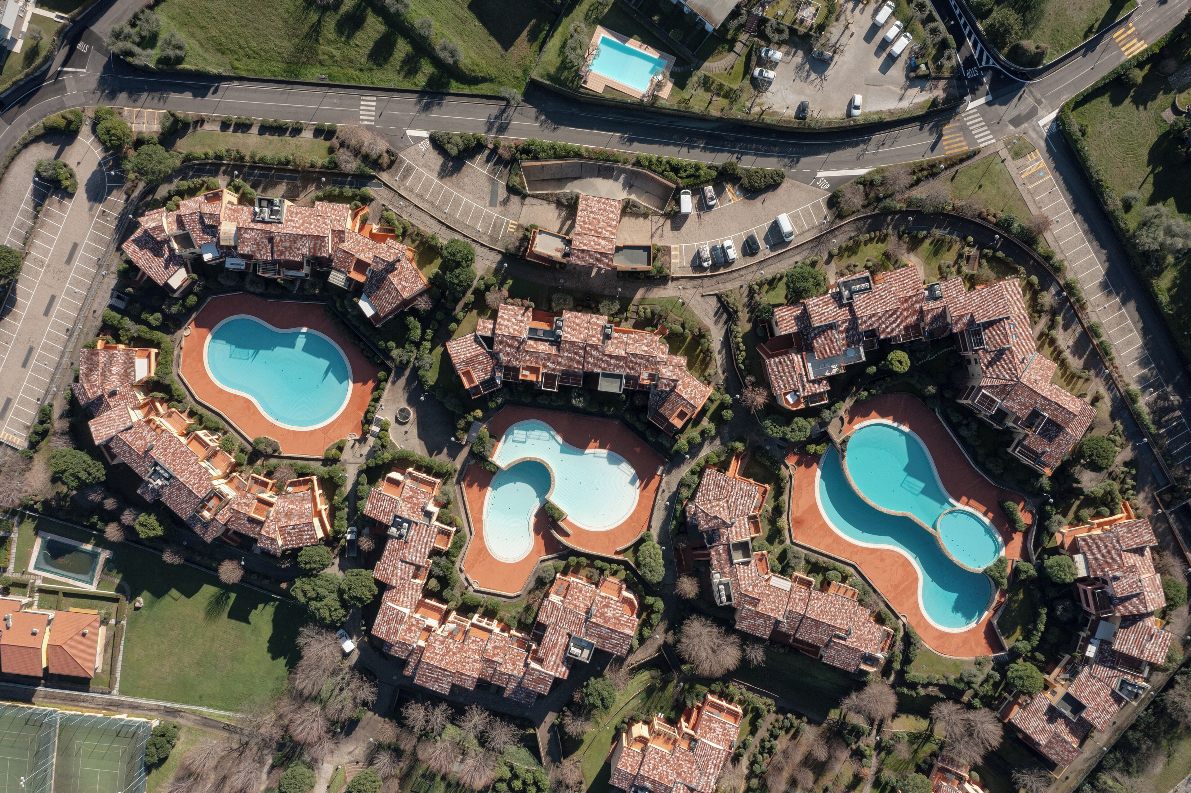 An aerial view of a residential area with multiple houses, each with a swimming pool.