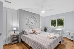 A bedroom with a bed, a round wall clock, a desk, and a window. - Charming remodeled 4th row House walk Beach, Coligny Plaza & Celebration Park! (Hilton Head Island)