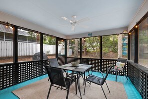 A covered patio with a table and chairs, a ceiling fan, and a view of the backyard. - Charming remodeled 4th row House walk Beach, Coligny Plaza & Celebration Park! (Hilton Head Island)