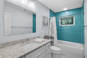 A bathroom with a bathtub, a toilet, a sink, and a window. - Charming remodeled 4th row House walk Beach, Coligny Plaza & Celebration Park! (Hilton Head Island)