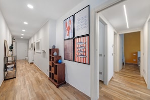 A hallway with wooden flooring, framed artwork, and a wooden shelf with decorative items. - Apartment 'Ca' Du Picciu' with Wi-Fi and Air Conditioning (Sestri Levante)
