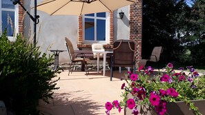 Eine Terrasse im Freien mit Tisch und Stühlen, einer Backsteinmauer und einem Fenster.
