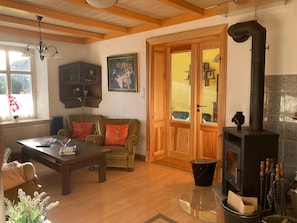 Ein gemütliches Wohnzimmer mit einem Holzsofa, einem Glastisch, einem Kamin und einem Holzkasten.
