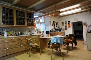 Eine Küche mit Holzausstattung, ein Essbereich mit Korbstühlen und eine Uhr an der Wand.