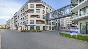 A modern hotel with a glass facade, multiple balconies, and a sign indicating a garden restaurant. - Modern Apartment with a Balcony | Pool, Spa, Gym (Międzyzdroje)