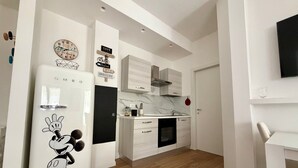 Eine moderne Küche mit einem Mickey Mouse Kühlschrank, einer Marmor-Spritzschutzwand und weißen Schränken.