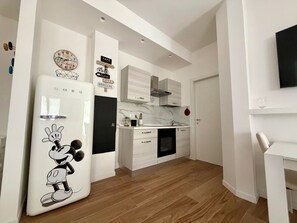 Eine moderne Küche mit einem Mickey Mouse Kühlschrank, einer Marmor-Spritzschutzwand und weißen Schränken.