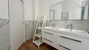 Ein modernes Badezimmer mit zwei Waschbecken, einem großen Spiegel und Holzboden.