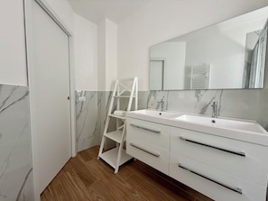 Ein modernes Badezimmer mit zwei Waschbecken, einem großen Spiegel und Holzboden.