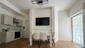 Eine moderne Küche mit weißen Schränken, einem eingebauten Backofen und einem Essbereich mit Tisch und Stühlen.