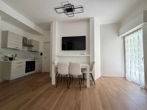 Eine moderne Küche mit weißen Schränken, einem eingebauten Backofen und einem Essbereich mit Tisch und Stühlen.