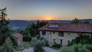 Edificio de piedra con techo de tejas, paneles solares y camino de entrada de grava.