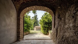 Un corredor de piedra con arco que conduce a un edificio de piedra con vistas a un jardín.
