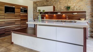 Uma cozinha moderna com parede de pedra, armários de madeira e uma ilha integrada.