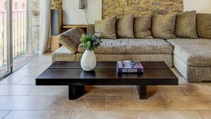 Uma sala de estar com parede de pedra, um sofá, uma mesa de centro e um abajur.