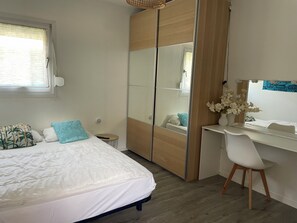 Ein Schlafzimmer mit Bett, Schreibtisch, Stuhl, Spiegel und einem Fenster mit Jalousien.
