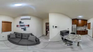 A modern living room with a grey sofa, a coffee table, and a kitchen area with wooden cabinets and a refrigerator. - Luxury apartment #4 steps away from IMSS / UMAE (Ciudad Obregón)