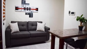 A modern living room with a sofa, a dining table, and a potted plant. - Luxury apartment #4 steps away from IMSS / UMAE (Ciudad Obregón)