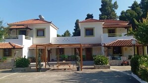 A two-story house with a covered patio area, a satellite dish, and a vehicle parked outside. - Skopelos Cozy Escape Near The Forest the Sea (Skopelos)