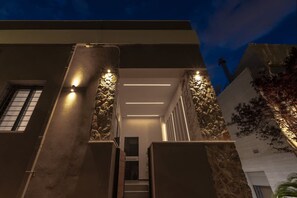 A modern building with a central staircase, stone pillars, and a well-lit entrance. - Green Blue Castella Luxury Suites Odyssey Suite (Piraeus)