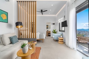 Una sala de estar moderna con sofá, una mesa de centro, televisión y vistas de la ciudad.
