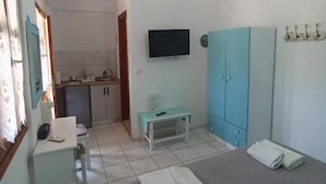 Un dormitorio con cama, escritorio, televisor, armario y ventilador de techo.
